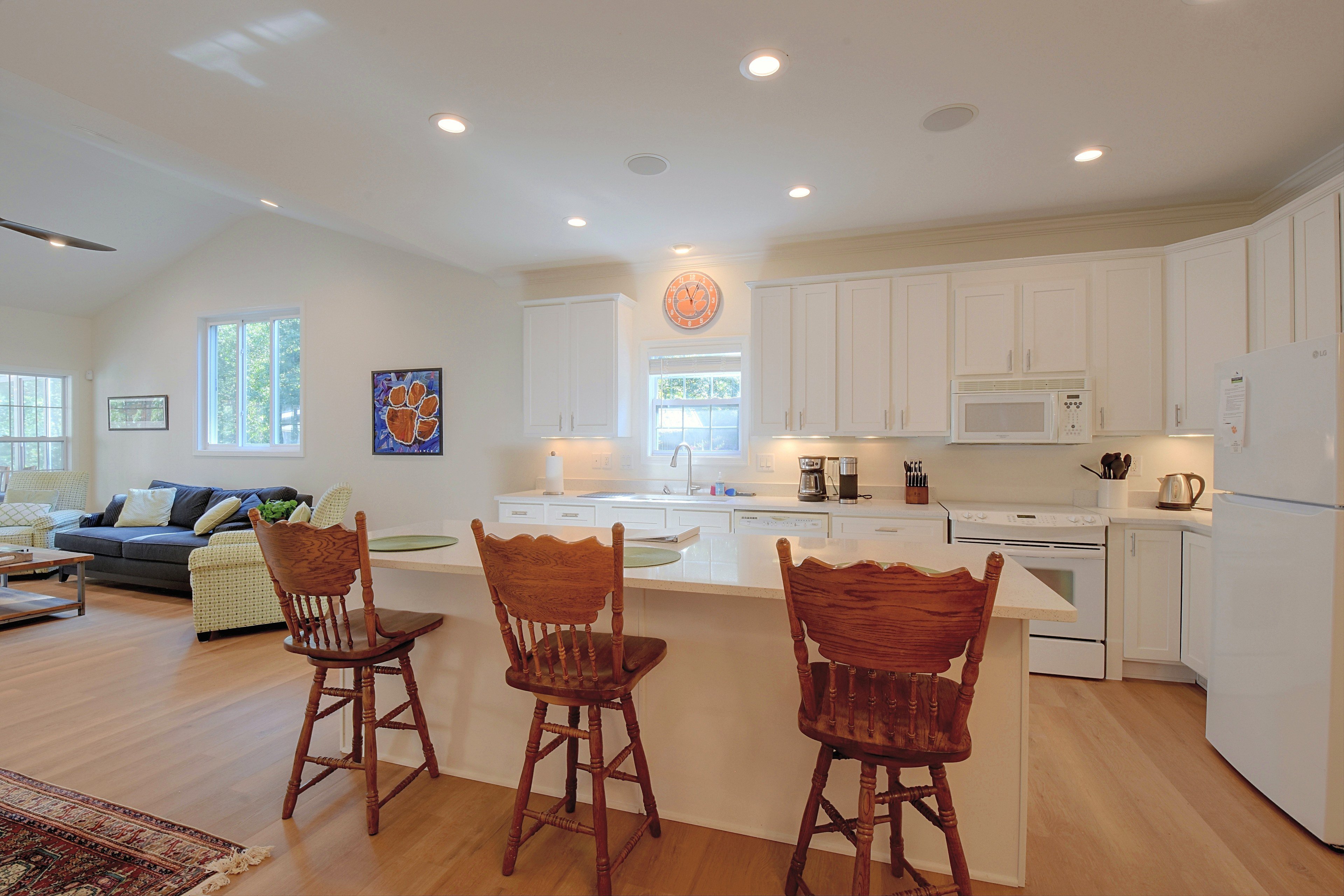 Fully equipped kitchen with white cabinetry, white appliances, and island bar seating.