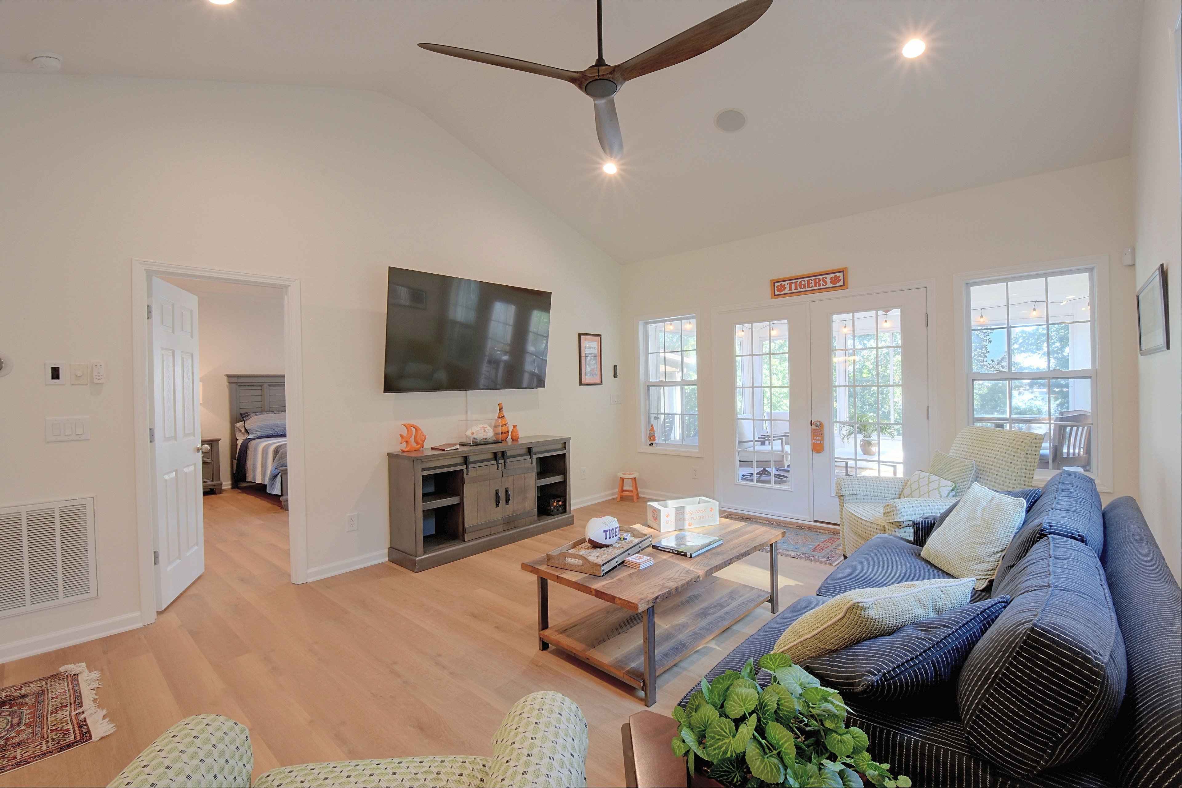 Main living room featuring vaulted ceilings, comfortable seating, and a wall-mounted TV.