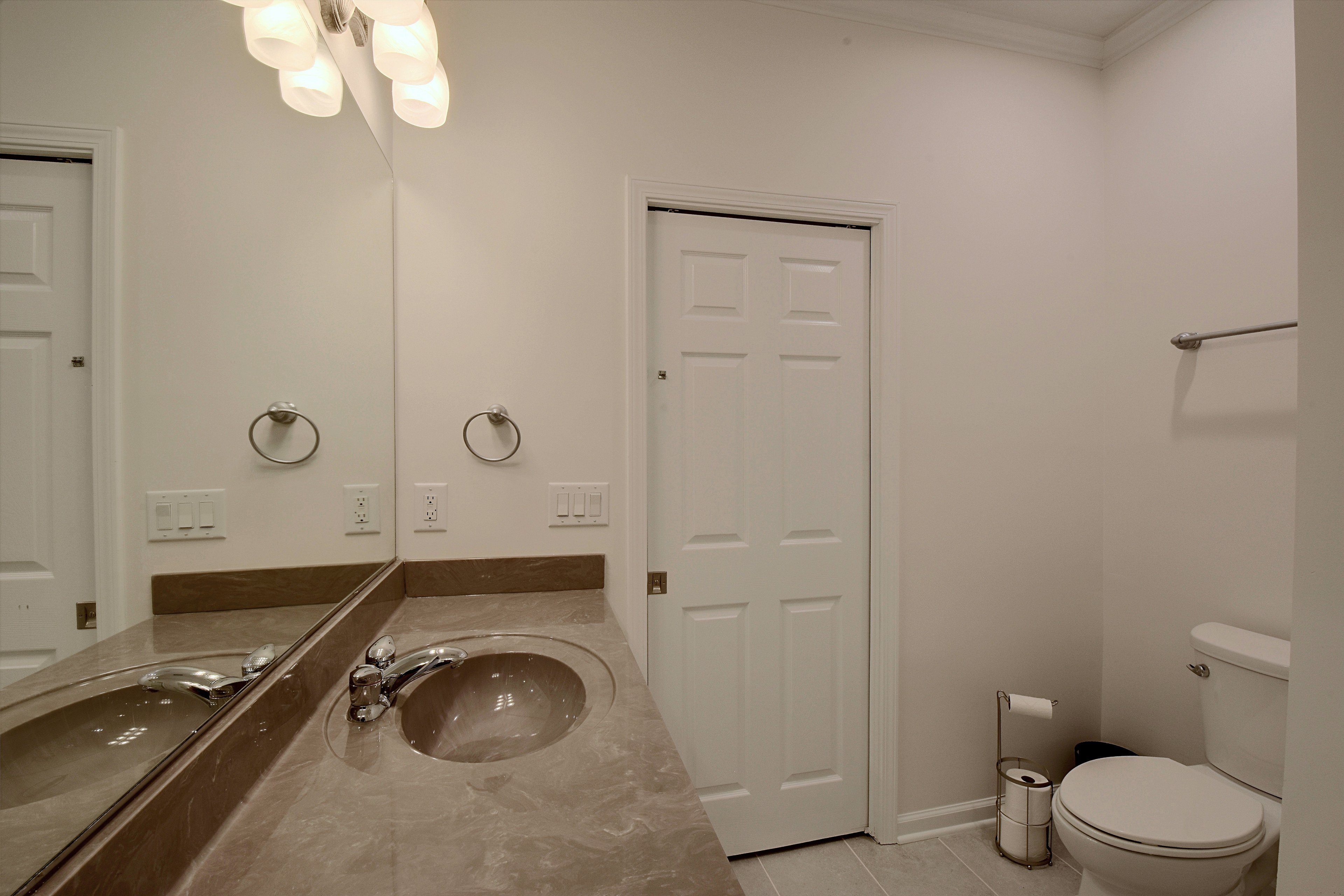Primary bathroom vanity and mirror next to toilet.