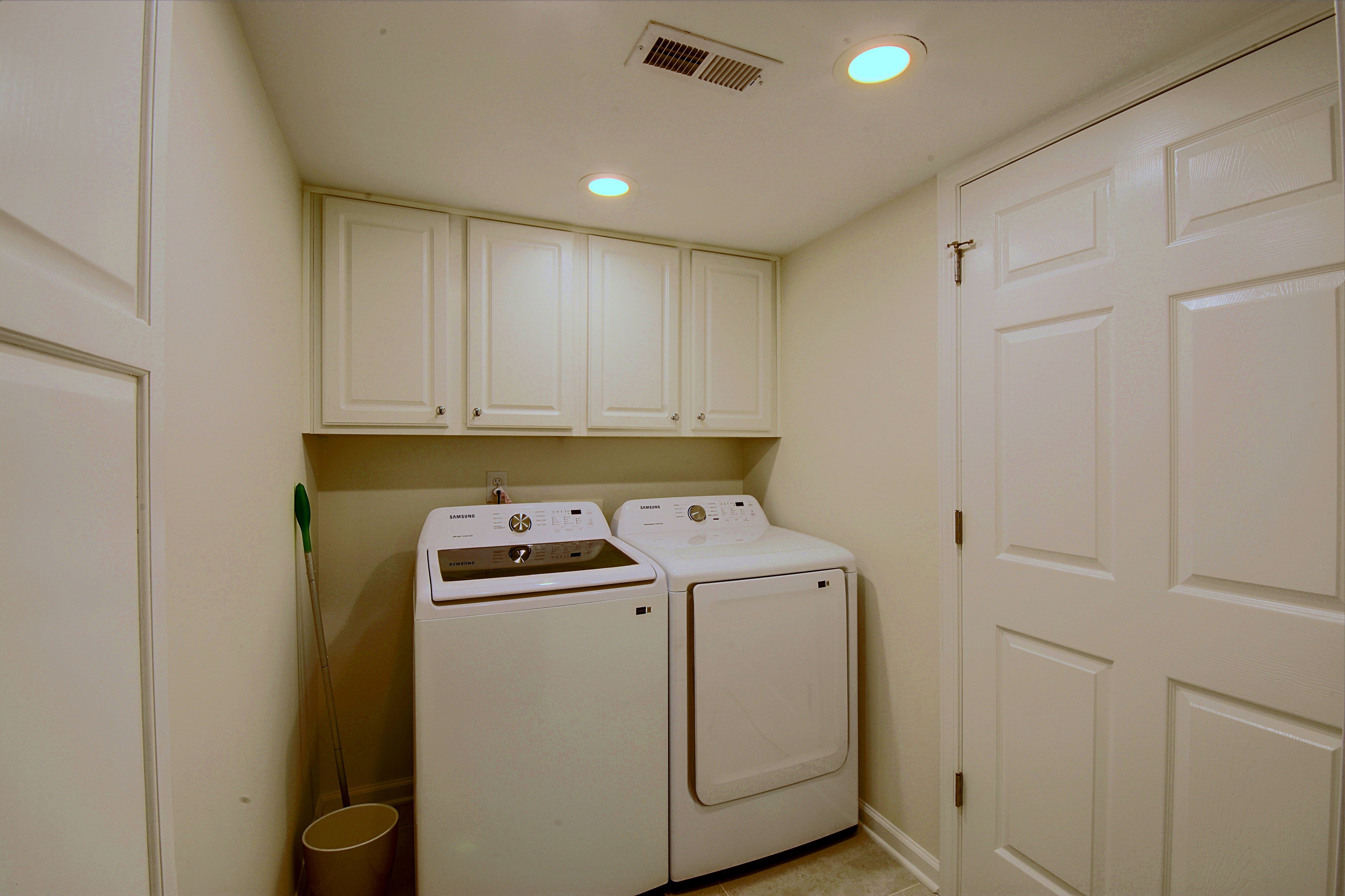 In-home laundry room equipped with washer, dryer, and storage cabinets.