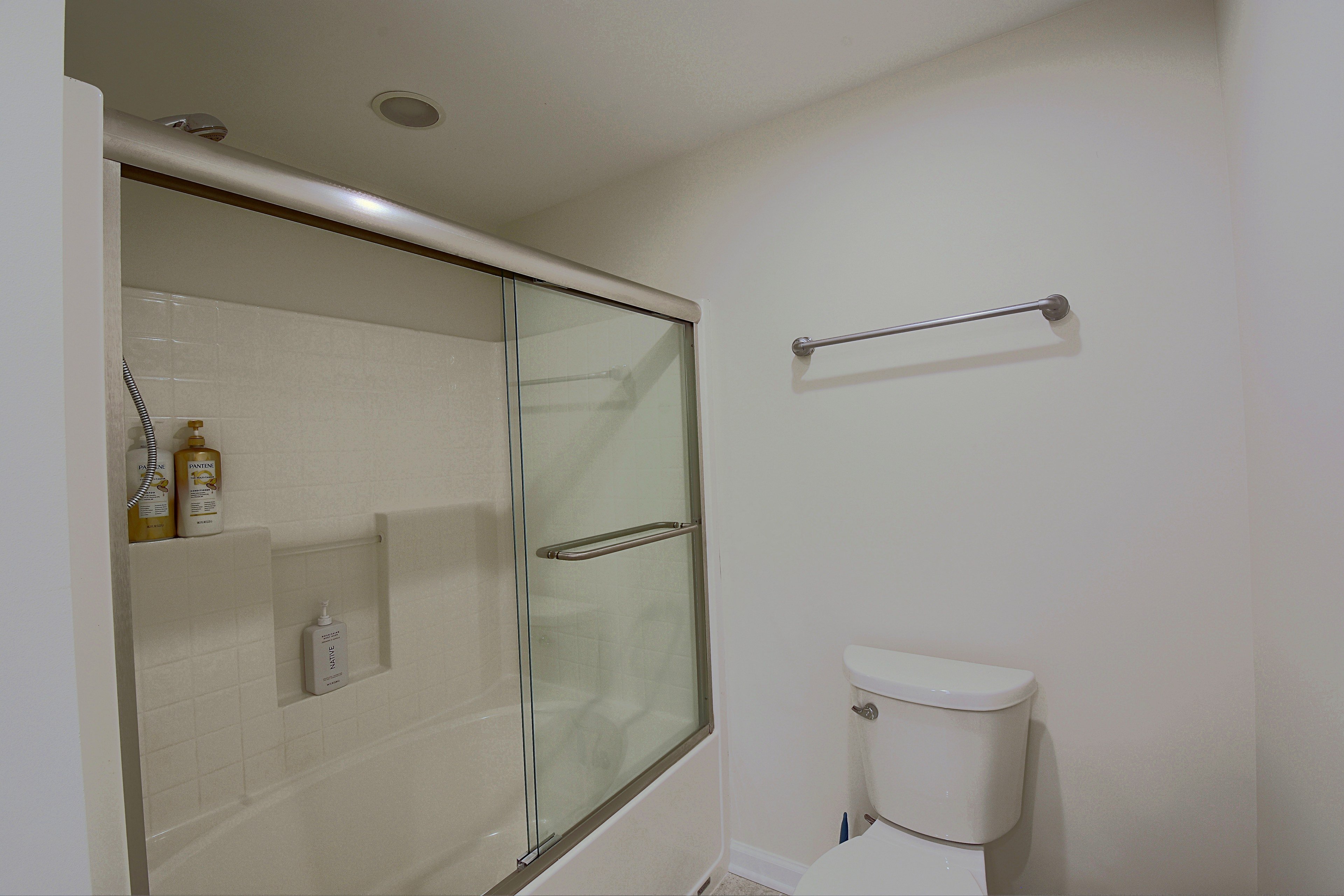 Bathroom featuring tub/shower combo with glass sliding door and toilet.