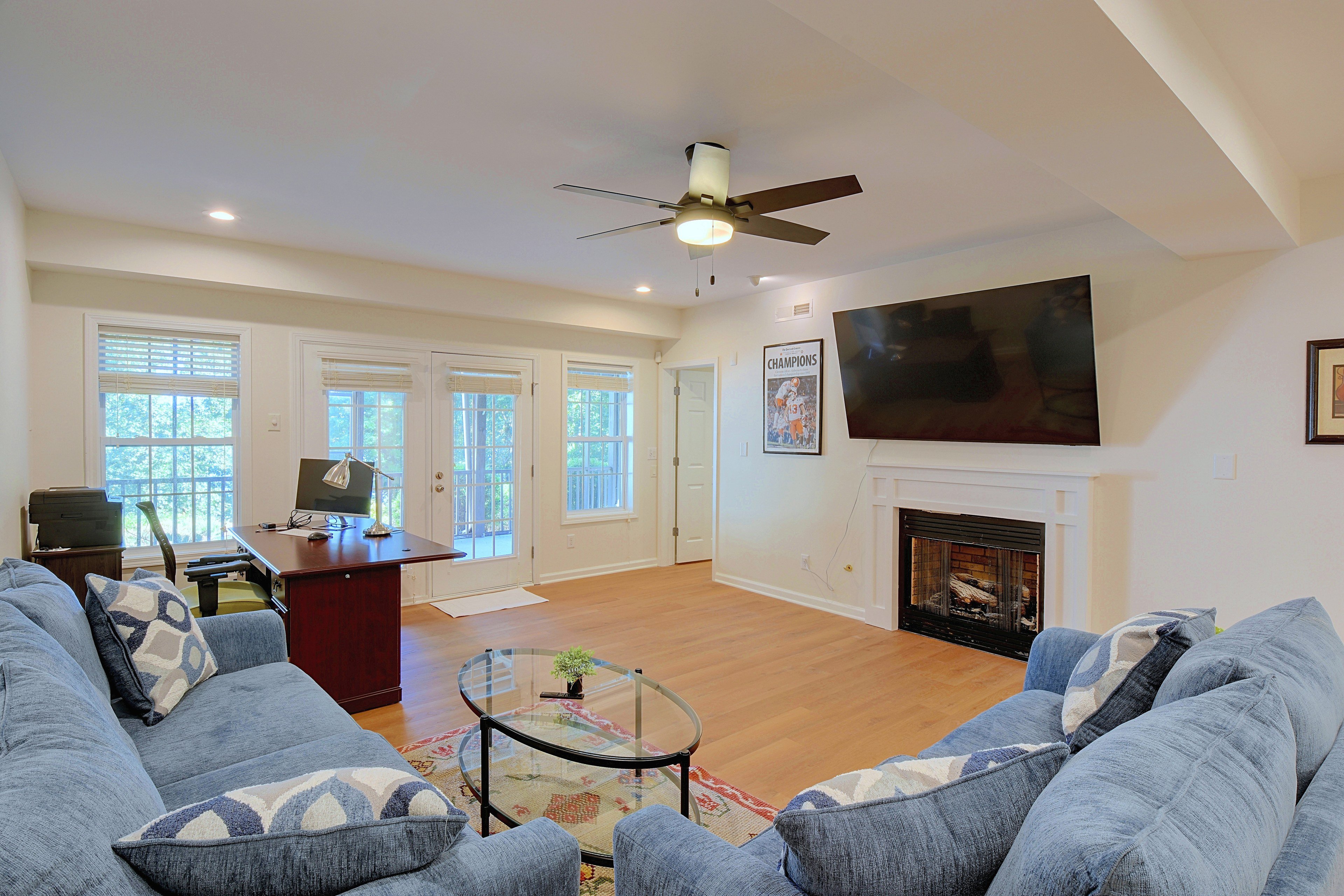 Lower-level rec room setup with desk, fireplace, and TV.