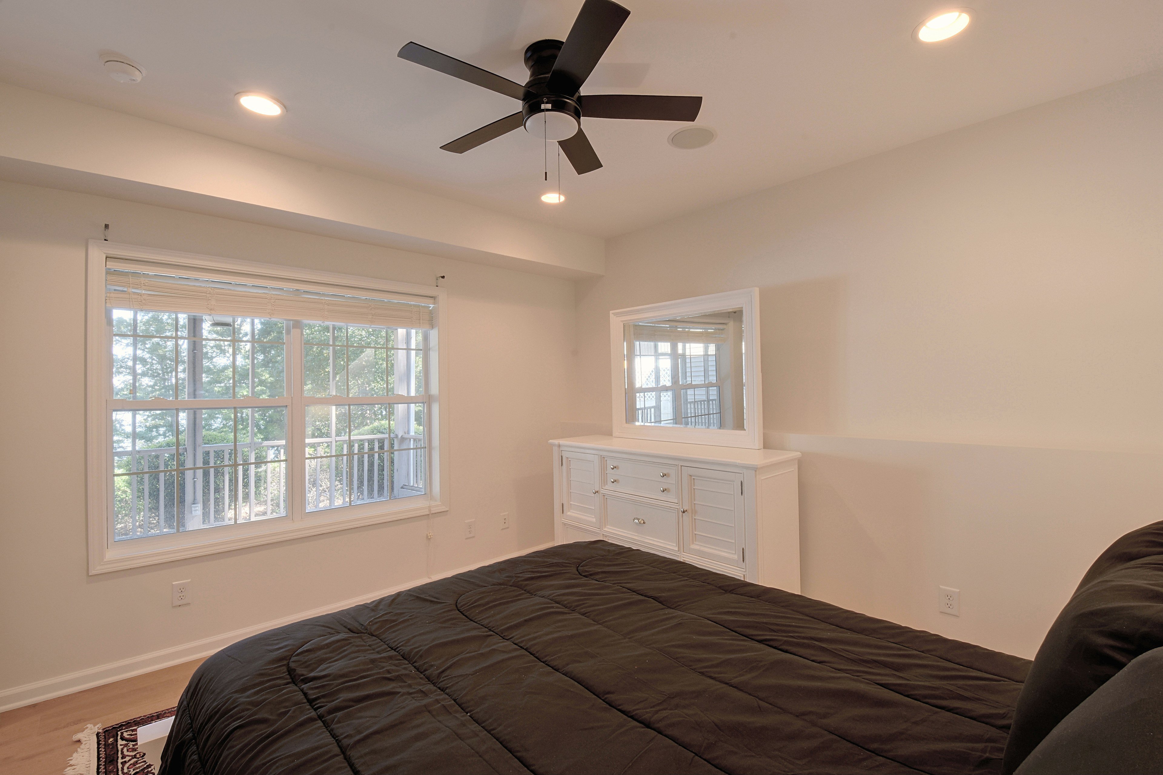 Second bedroom with white dresser, mirror, and area rug.