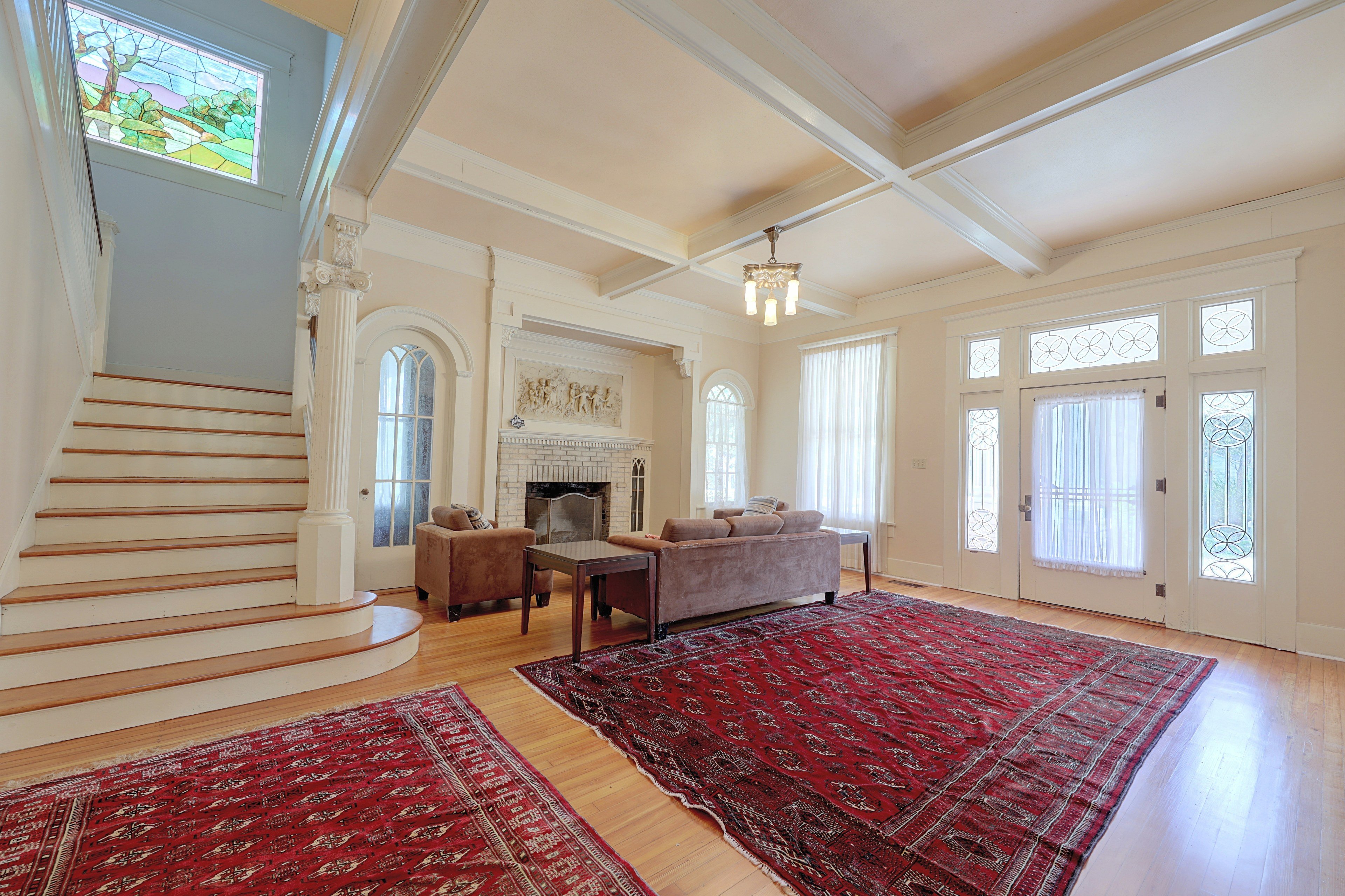Sprawling living room featuring hardwood floors, a cozy fireplace, and grand staircase.