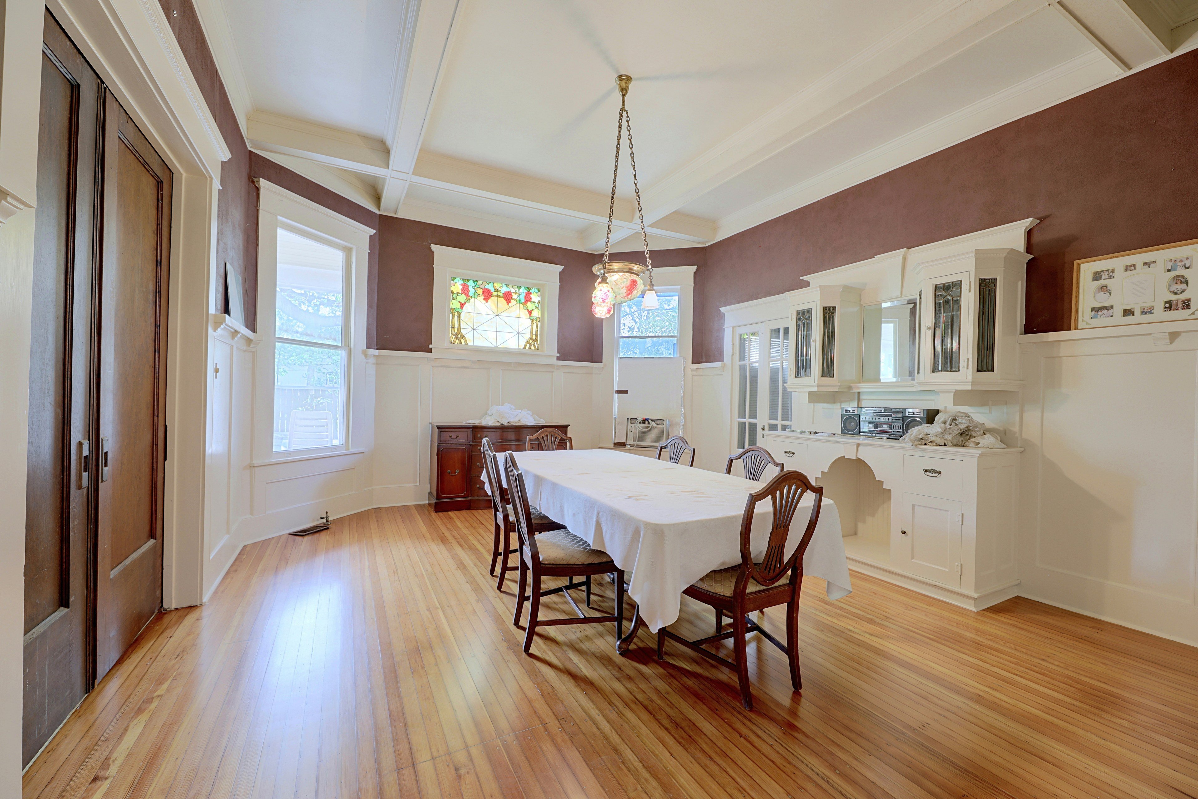 Formal dining room featuring wainscoting, burgundy walls, a long dining table, and built-in hutch.
