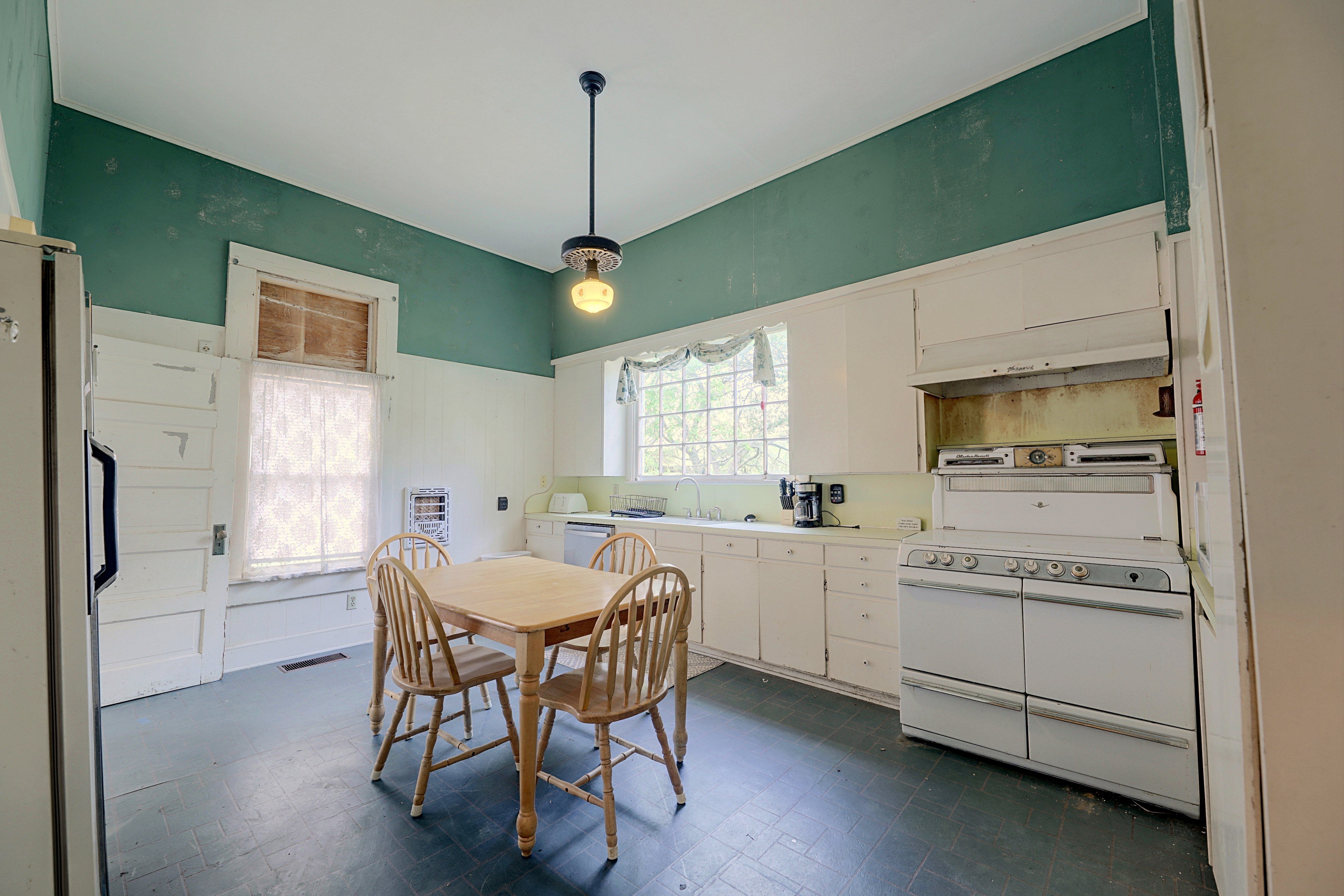 Eat-in kitchen with green accent walls, white cabinetry, a vintage-style stove, and dining table.