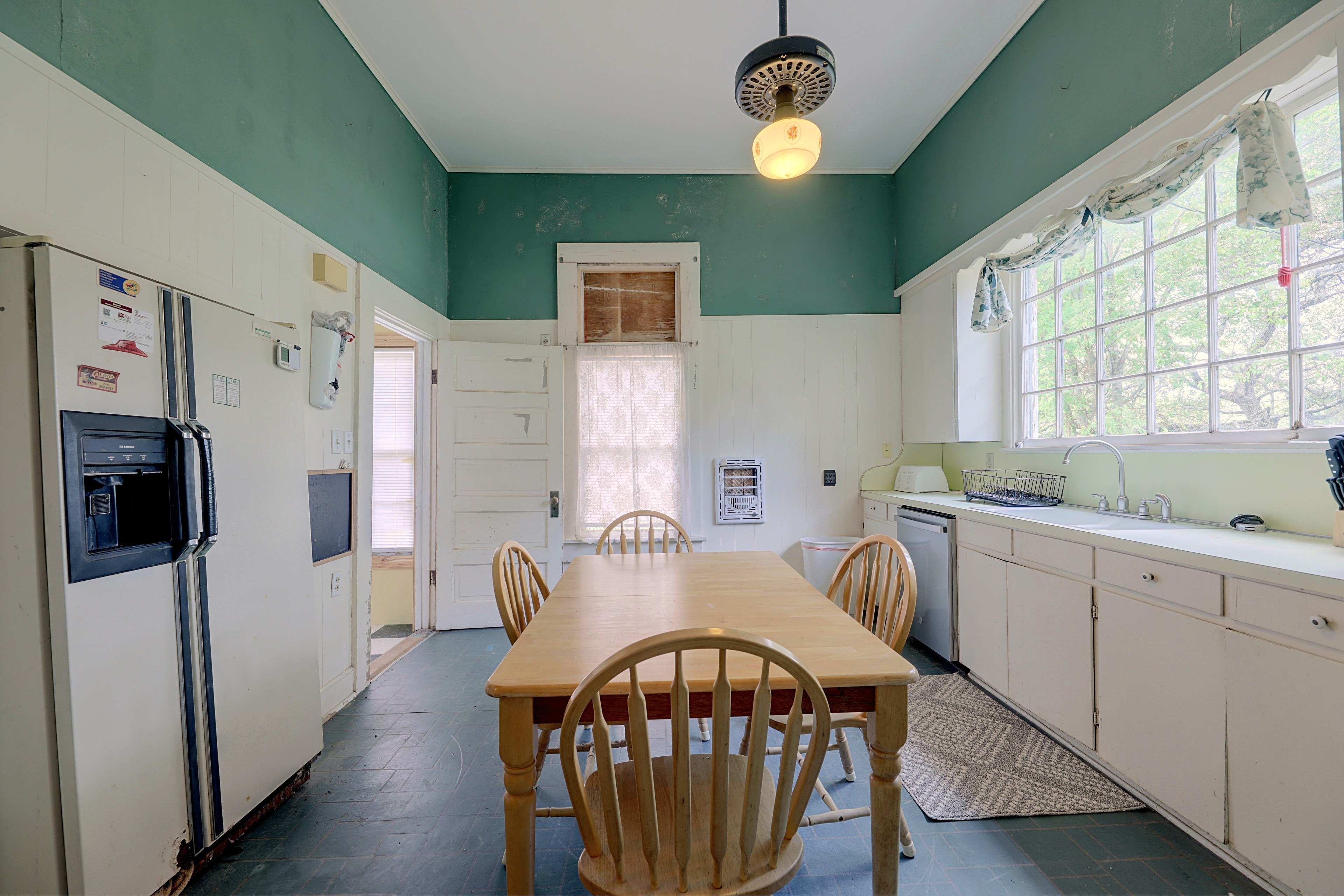 Kitchen view showing the refrigerator, dining set, and large window above the sink.