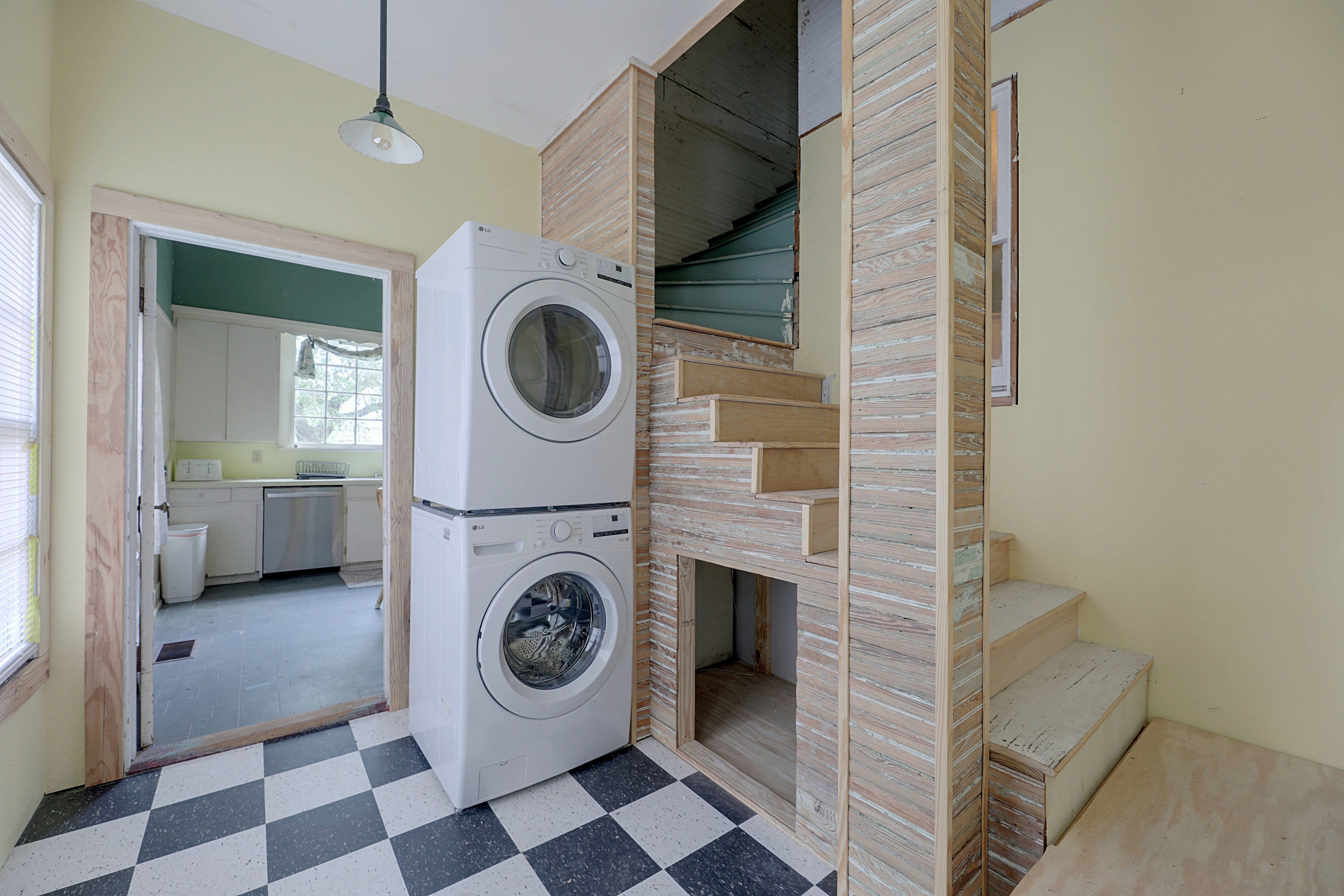 Laundry space equipped with a stacked washer and dryer set and checkerboard tile floor.
