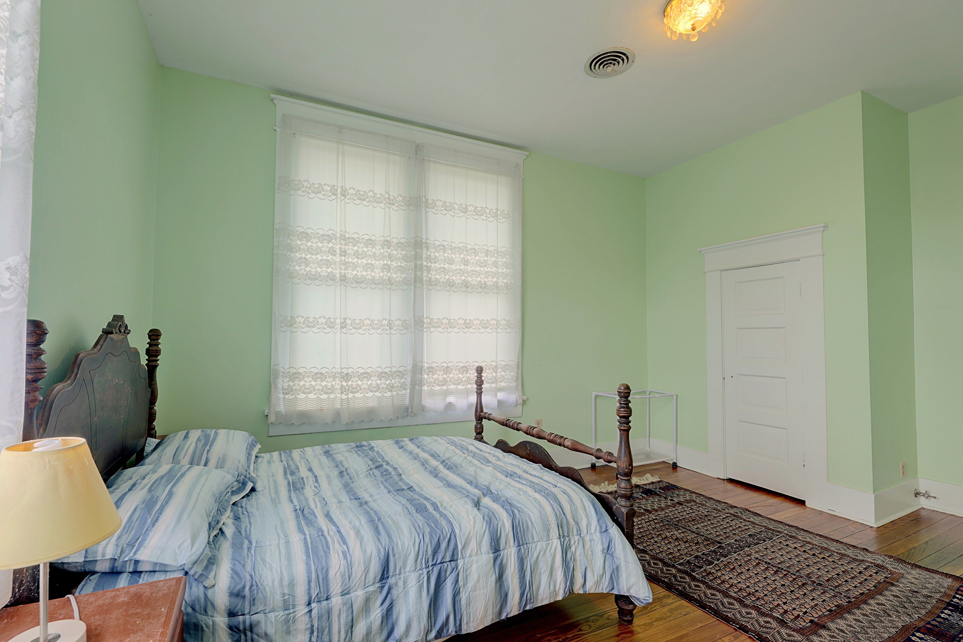 Alternate view of the green bedroom showing the layout and entry door.