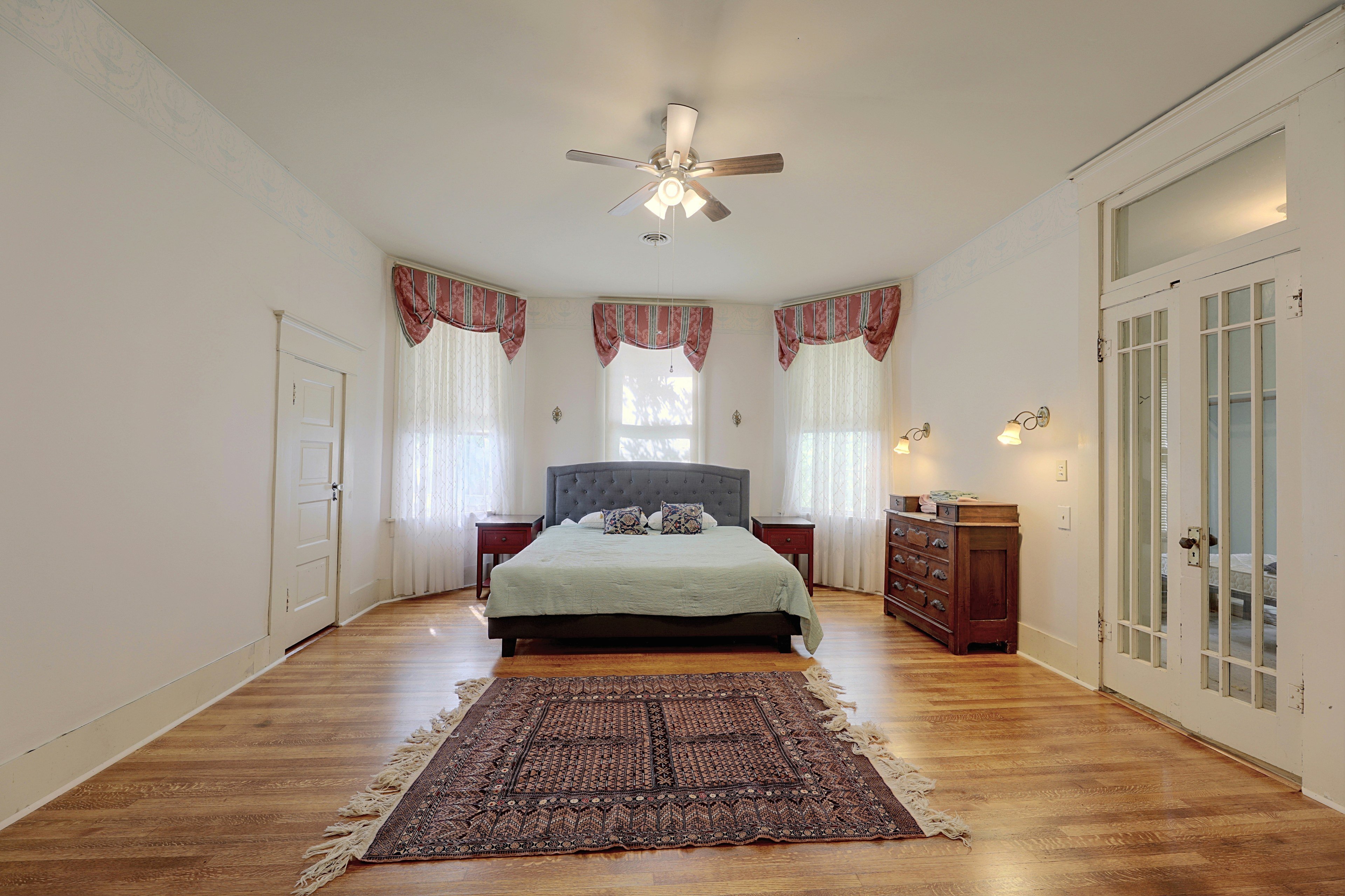 Primary bedroom centered around a comfortable bed with bay windows in the background.