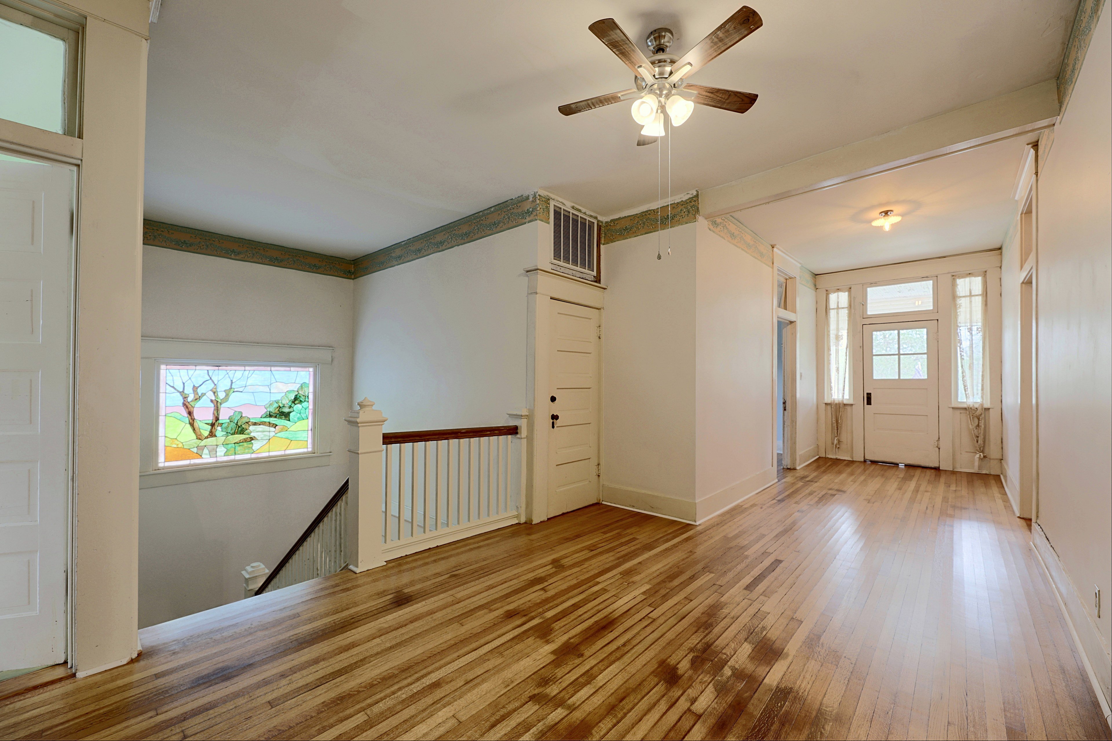 Open upper hallway with hardwood floors, ceiling fan, and access to bedrooms.