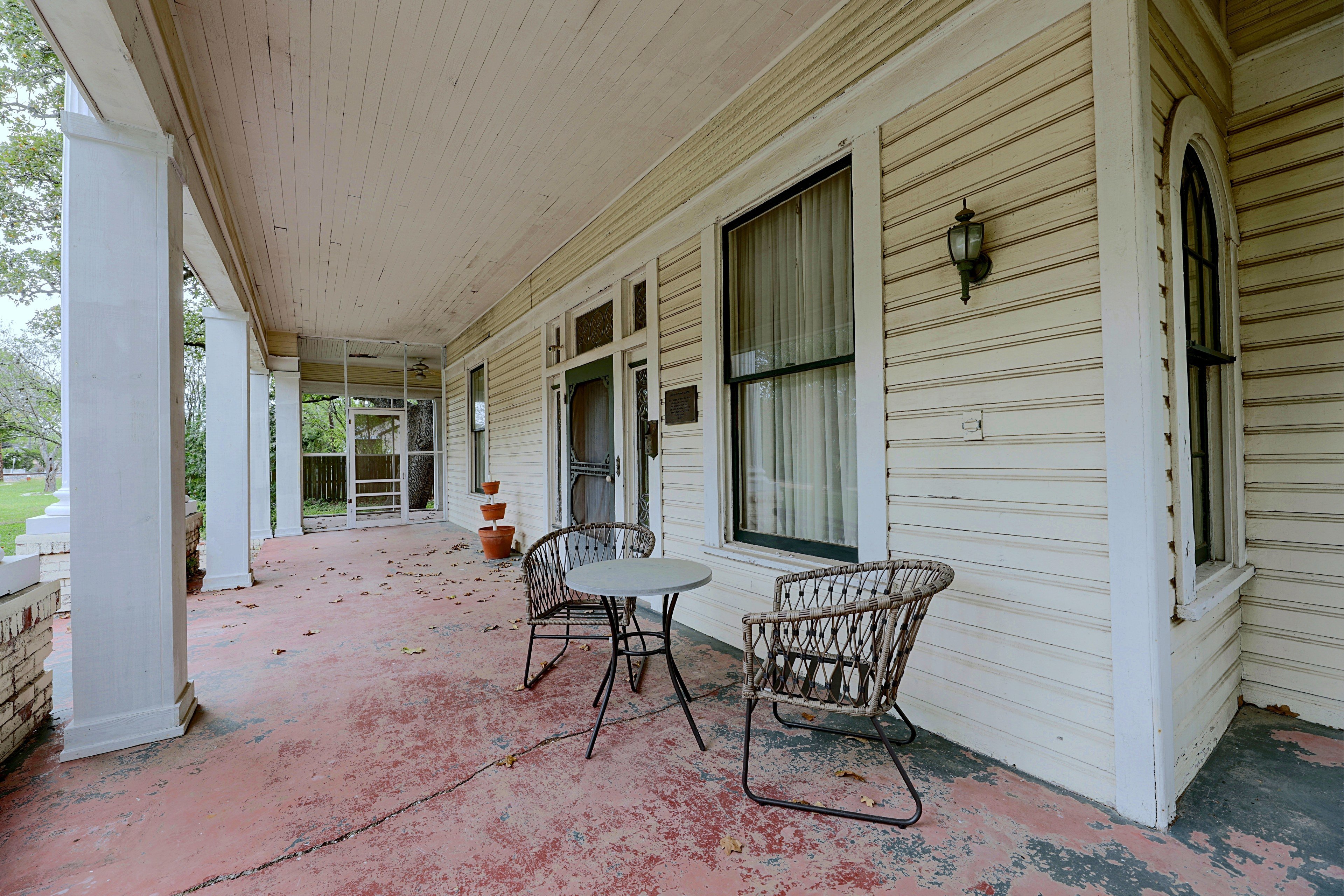 Covered front porch equipped with a small bistro table and chairs.