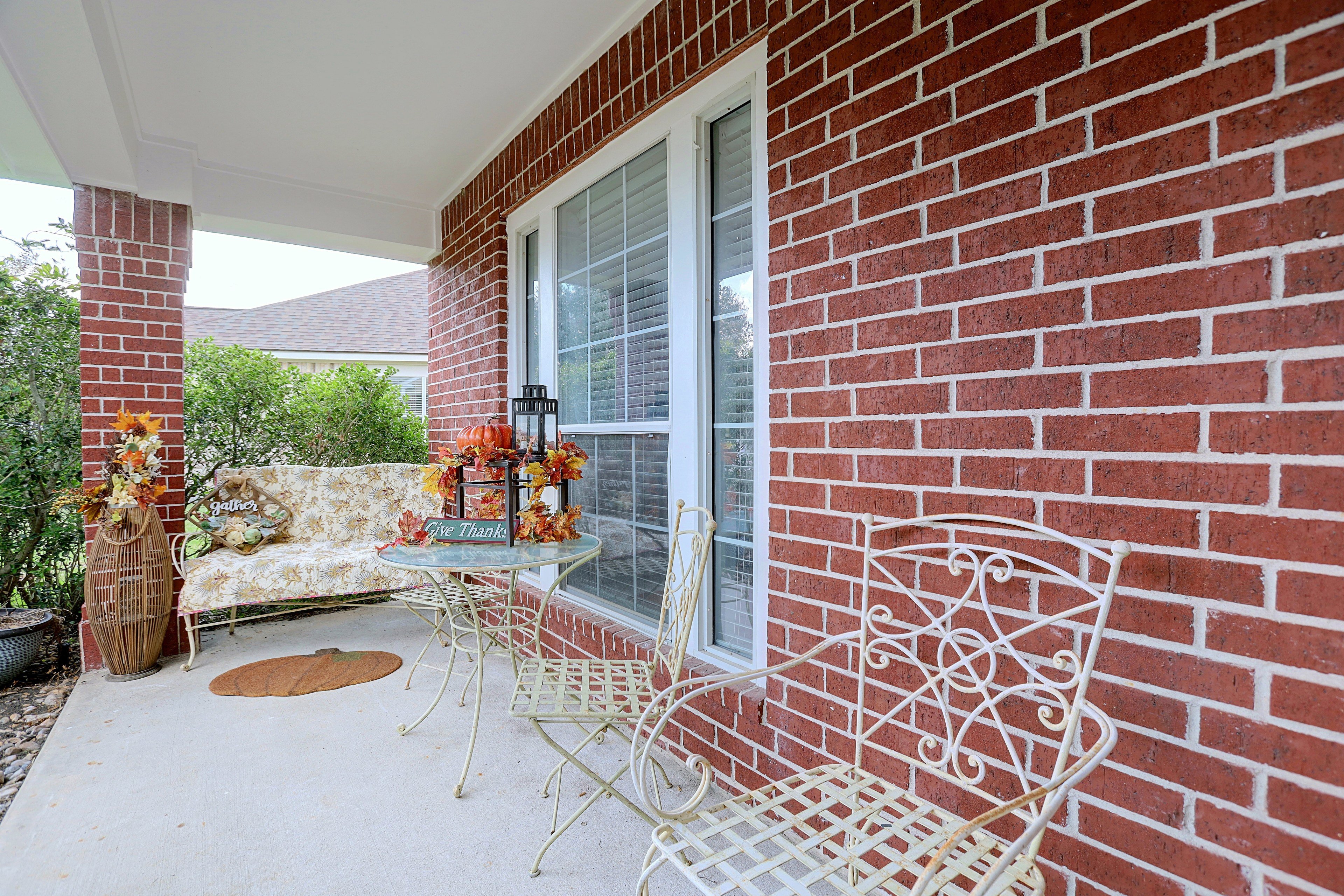 Covered front porch area with outdoor seating bench and table.