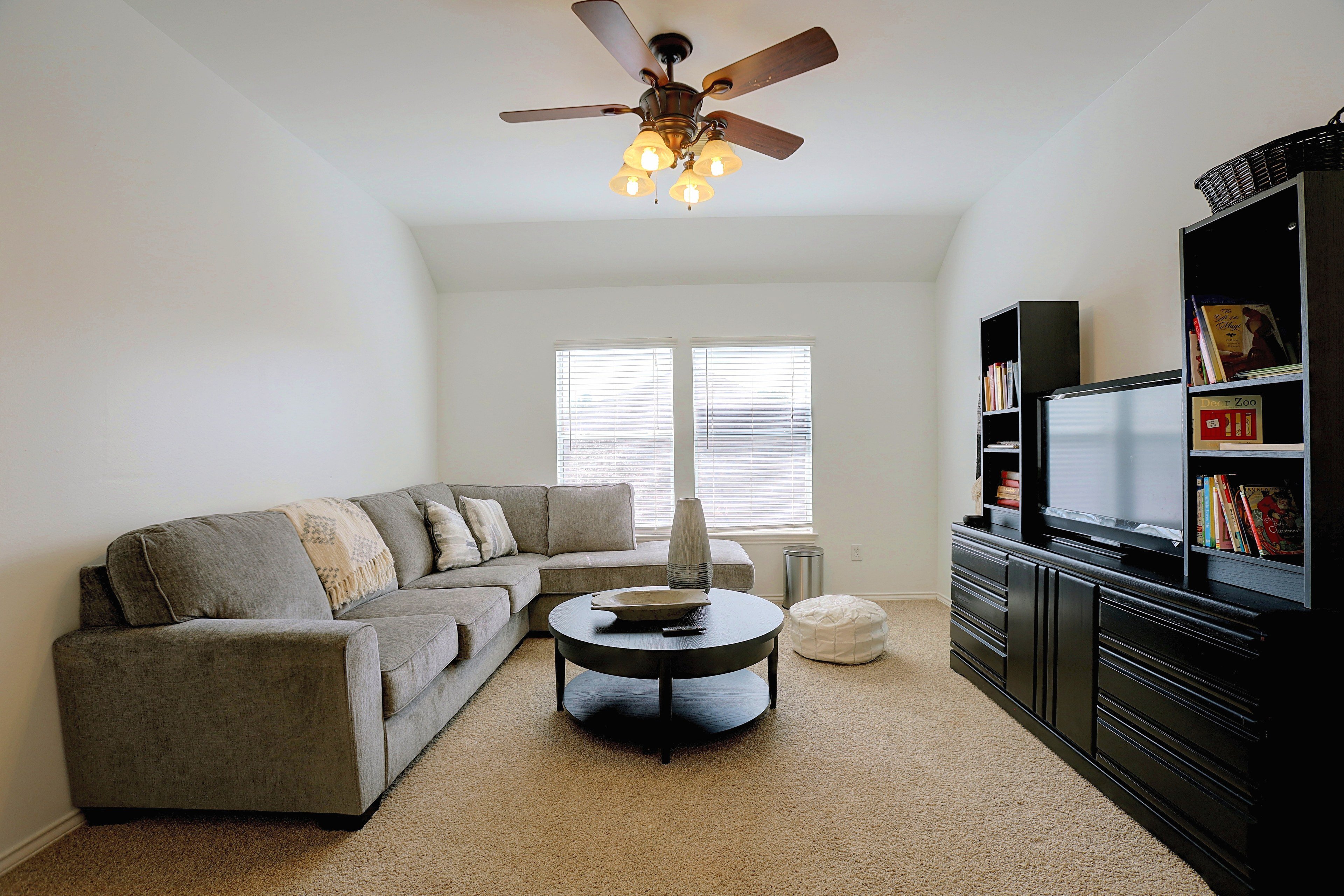 Upstairs family room with grey sectional sofa and TV entertainment center.