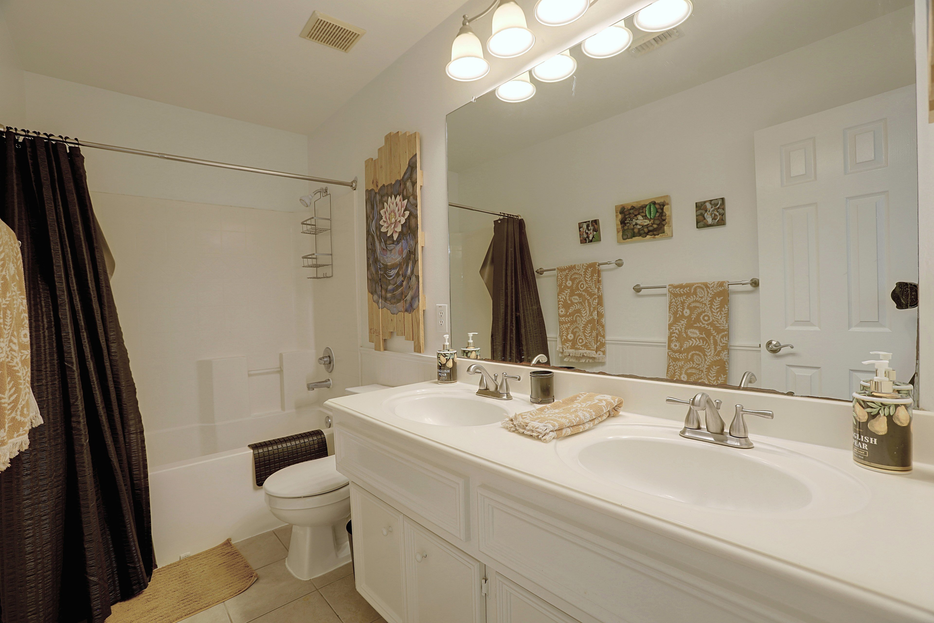 Full secondary bathroom featuring a double vanity sink and tub/shower combination.