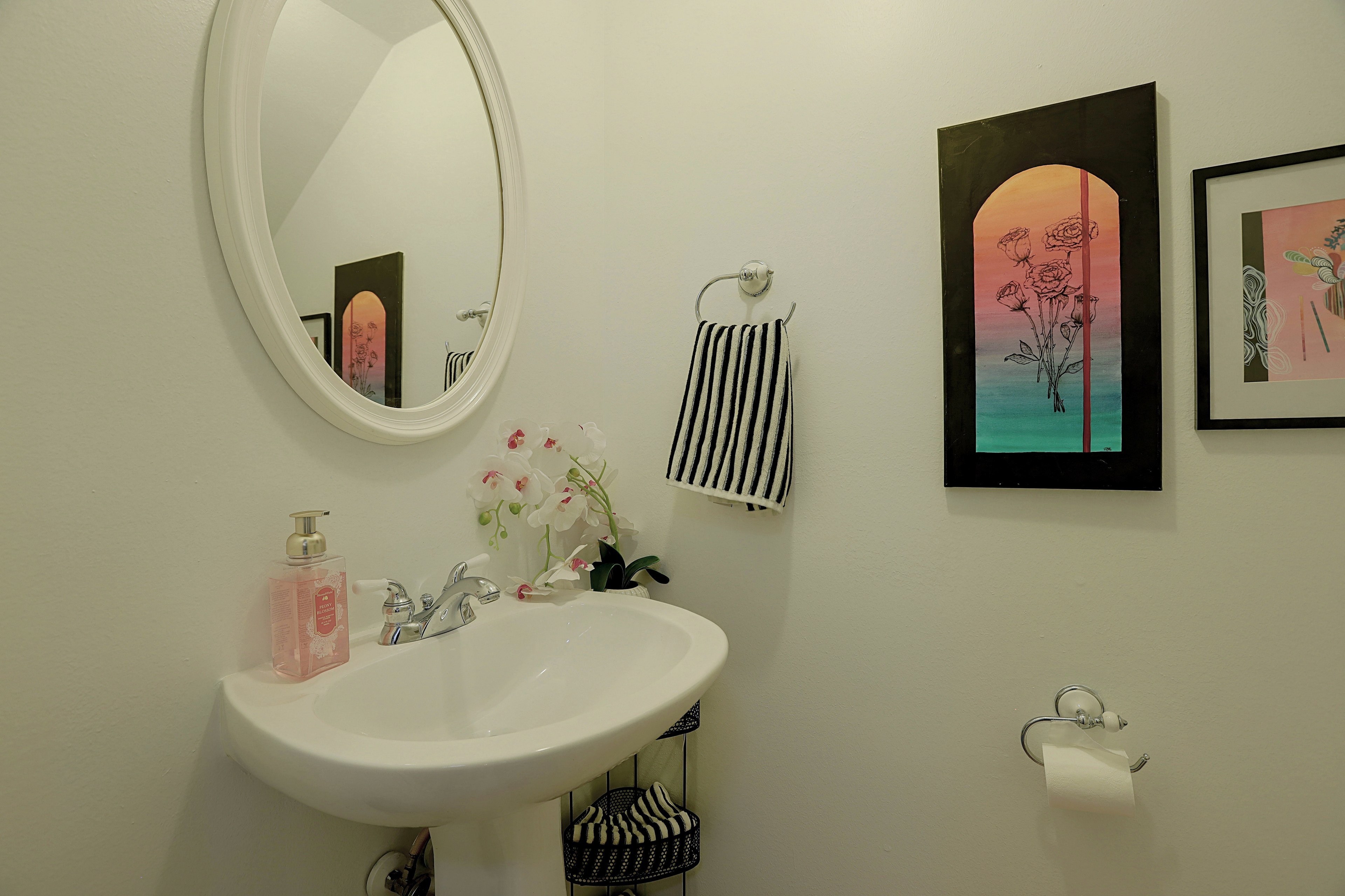 Powder room with white pedestal sink and oval wall mirror.