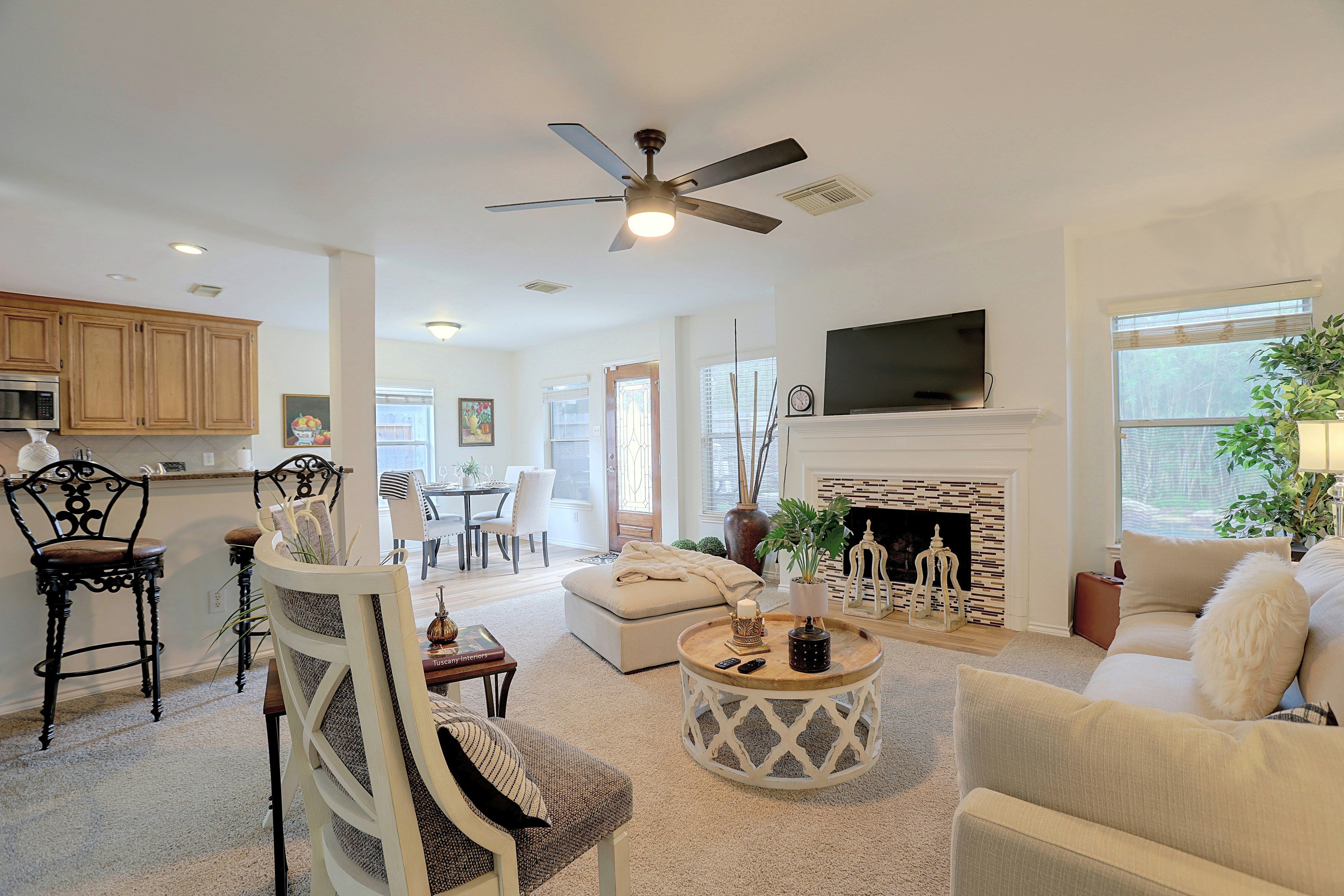 Open-concept main living room with carpeted seating, fireplace, and view into the kitchen area.
