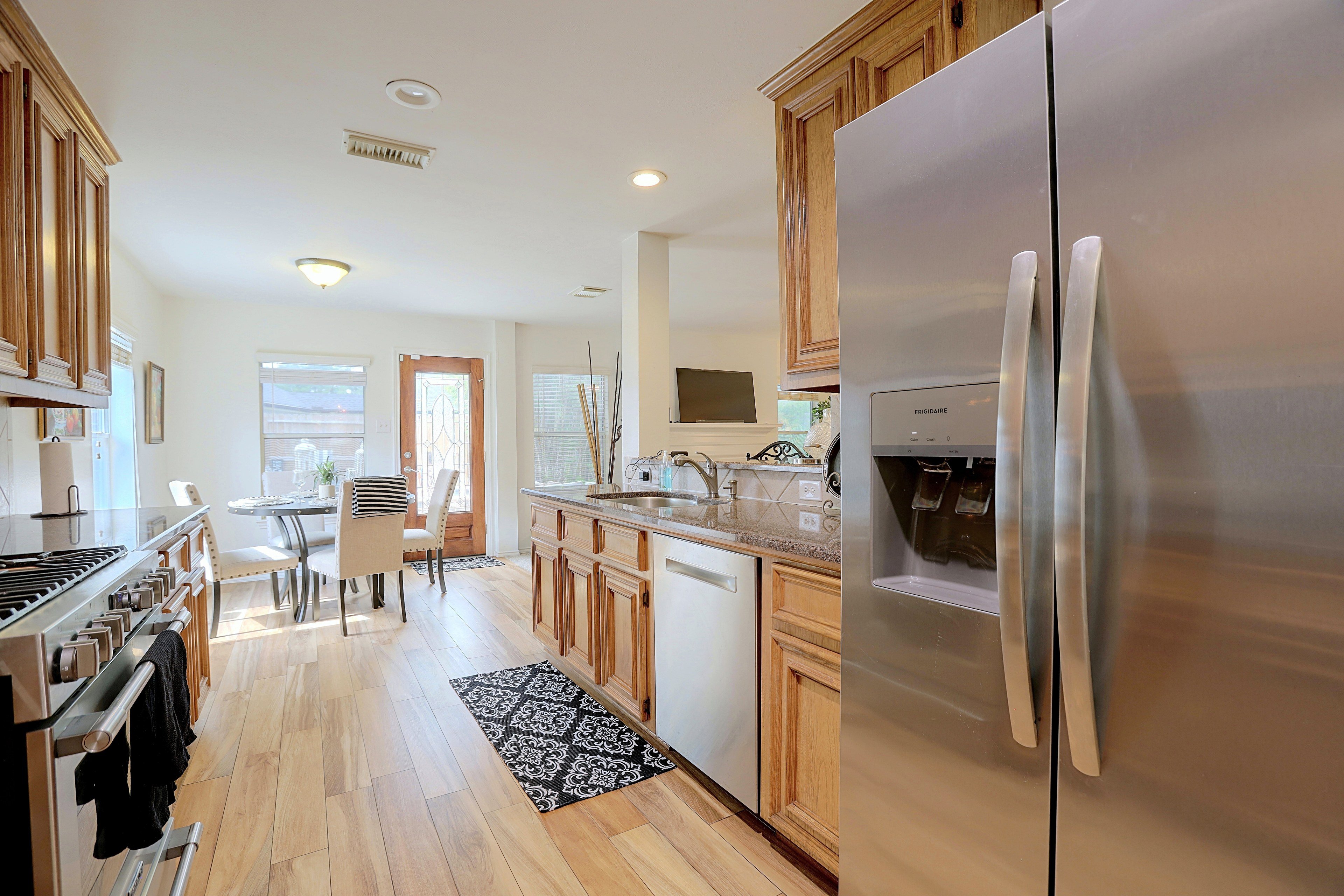 Kitchen aisle looking toward stainless steel refrigerator.