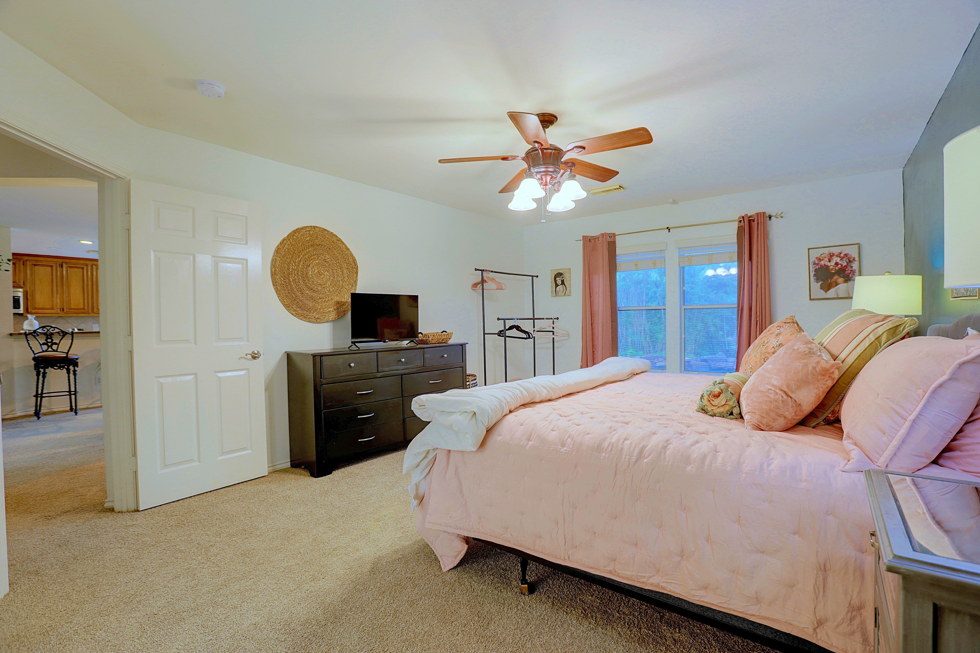 Primary bedroom window view with pink drapes and carpeted floor.